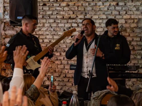 Cantante, bajista y tecladista tocando en vivo frente a la pared de ladrillo