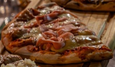 Pizza con jamón y muzzarella gratinada sobre tabla de madera